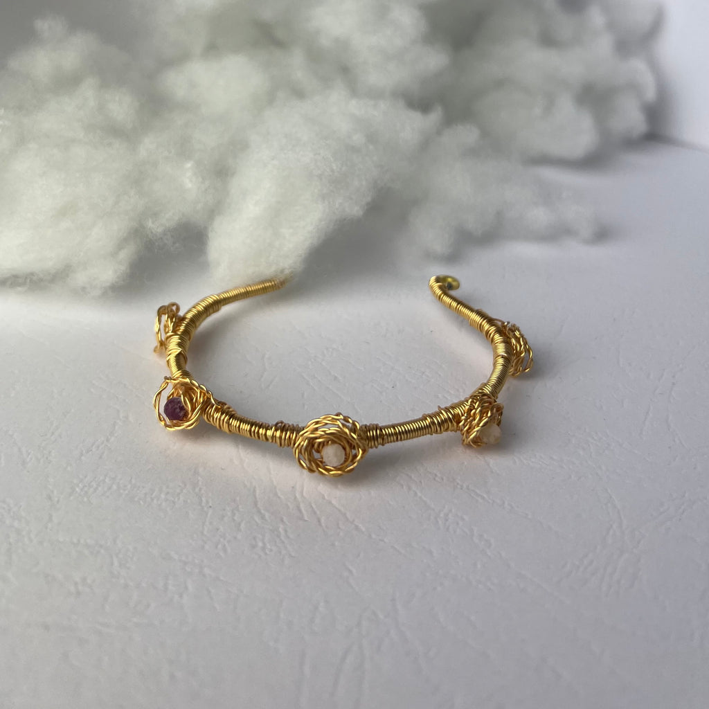 Złota bransoletka wire wrapping z rubinem cytrynem i kryształem górskim na białym tle chmurki